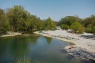 Mehrere Menschen liegen in der Sonne am Isarstrand beim Flaucher in München