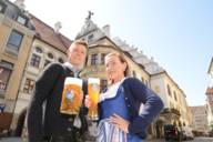 Junger Mann mit Maß Bier und junge Frau mit Weißbier vor dem Hofbräuhaus in München