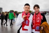 Bayern Fans aus China stehen auf der Esplanade vor der Allianz Arena in München.