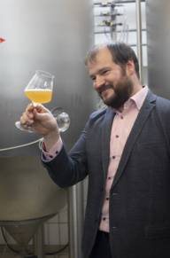Ein Mann hält ein Glas mit Bier in der Hand und betrachtet dieses.