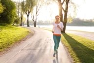 Eine Frau joggt in der Abendsonne durch den Olympiapark in München.